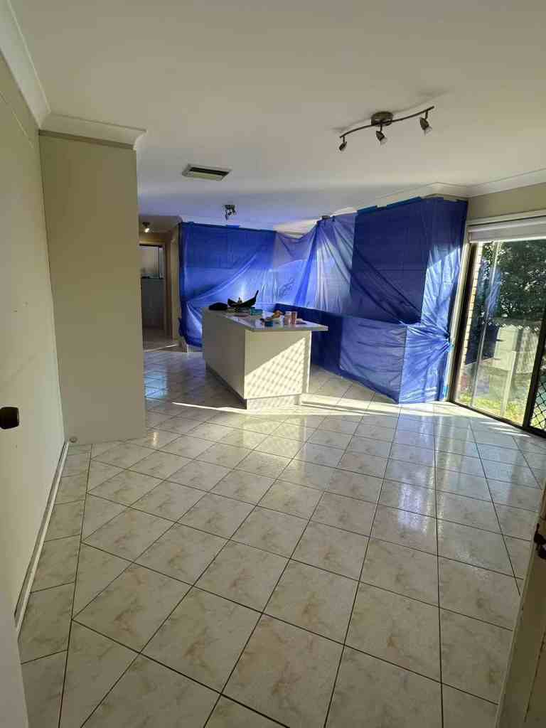 Open living area under renovation with blue protective coverings and kitchen island.